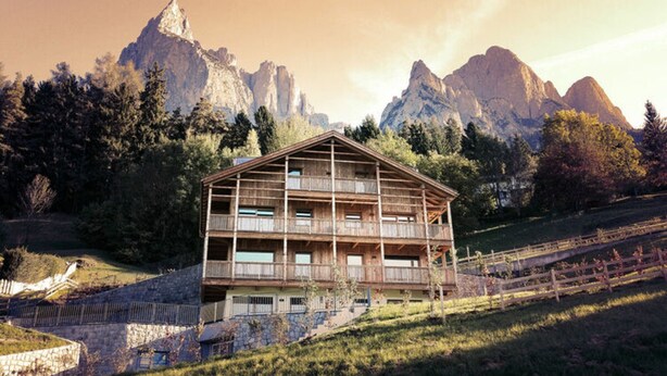 Un chalet en bois doté de plusieurs balcons, situé dans un cadre montagneux.
