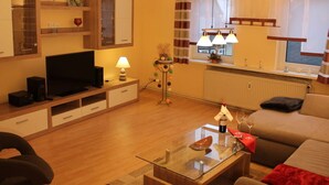 A living room with a TV, sofa, glass coffee table, and a lamp. - 2 am Lustgarten Modern Retreat (Wernigerode)