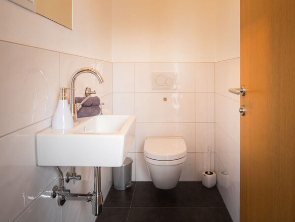 A modern bathroom with a white sink, a toilet, and a bidet. - in the Holiday Home Sandra Comfortable Holiday Residence (Hoerbranz)
