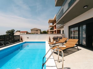 A rooftop pool area with a clear blue pool, wooden lounge chairs, and a metal pool ladder. - Villa La Ze - Three Bedroom Villa With Swimming Pool (Rogoznica)