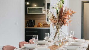 Una mesa de comedor decorada con platos blancos, vasos y un centro de mesa con flores secas y follaje.