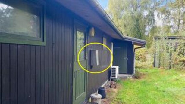 A wooden house with a dark exterior, a visible door, and a small step leading to the entrance. - 5 Person Holiday Home in Melby (Melby)