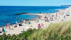 A beach with people, tents, and a lifeguard tower. - 5 Person Holiday Home in Melby (Melby)