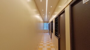 Un couloir d’hôtel avec un sol à carreaux, un éclairage encastré et des portes munies de barreaux.