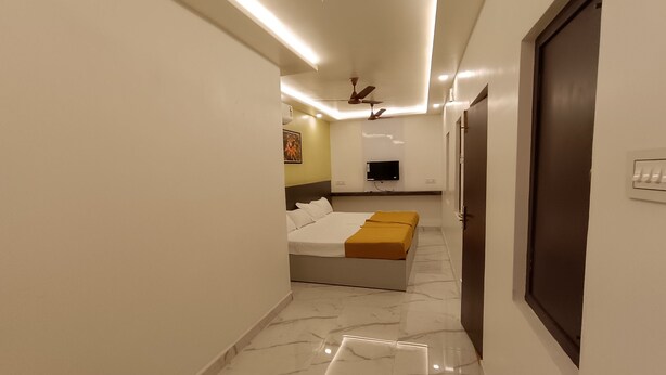 Une chambre d’hôtel moderne équipée d’un lit, d’une télévision et d’un ventilateur de plafond.