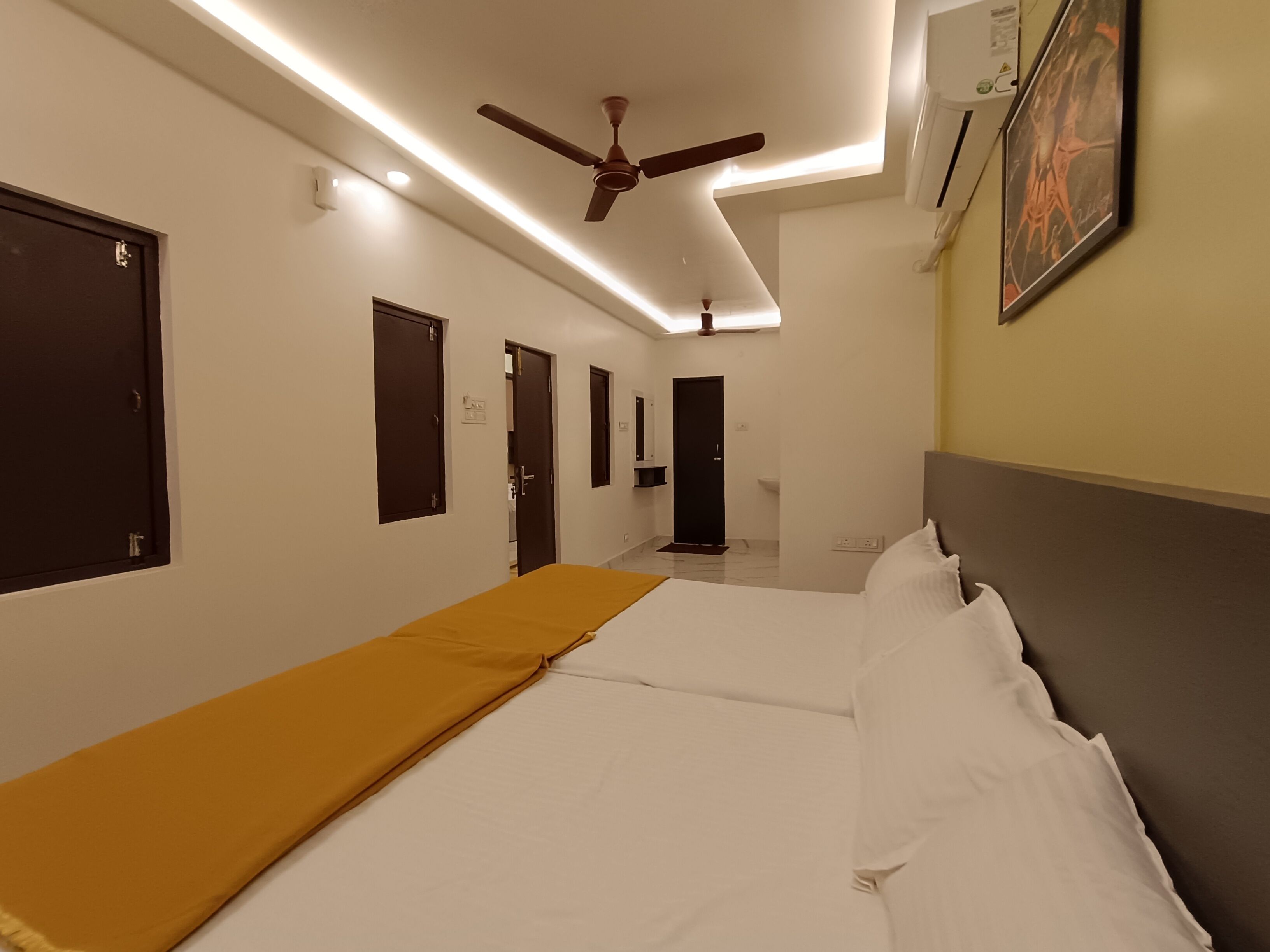 Een hotelkamer met een bed, een plafondventilator en een wandairconditioner.