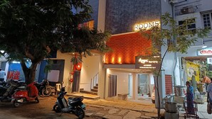 Un bâtiment avec une enseigne indiquant « CHAMBRES » et une autre pour « Airtel Freshness ». On peut voir des scooters garés devant, ainsi qu’un arbre.