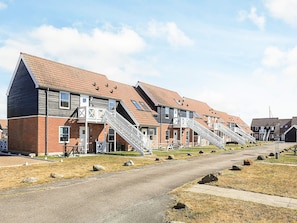 A row of modern apartment buildings with external staircases leading to the entrance.