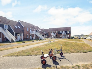 A row of brick buildings with external staircases and a gravel pathway in front.