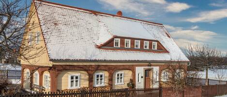 A traditional chalet with a sloped roof, wooden facade, and a fenced yard.