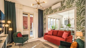 Een moderne woonkamer met een rode bank, groene fauteuils en een vloerkleed met een patroon.