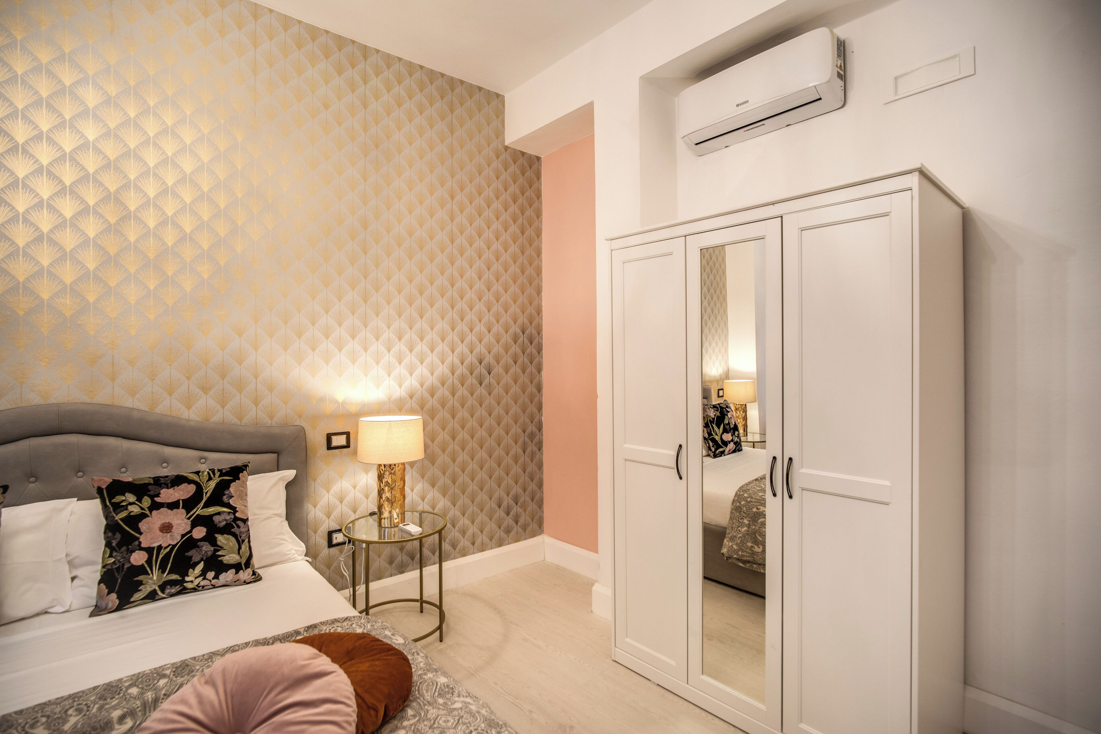 Camera da letto con un letto, comodino, lampada, armadio e parete decorata.