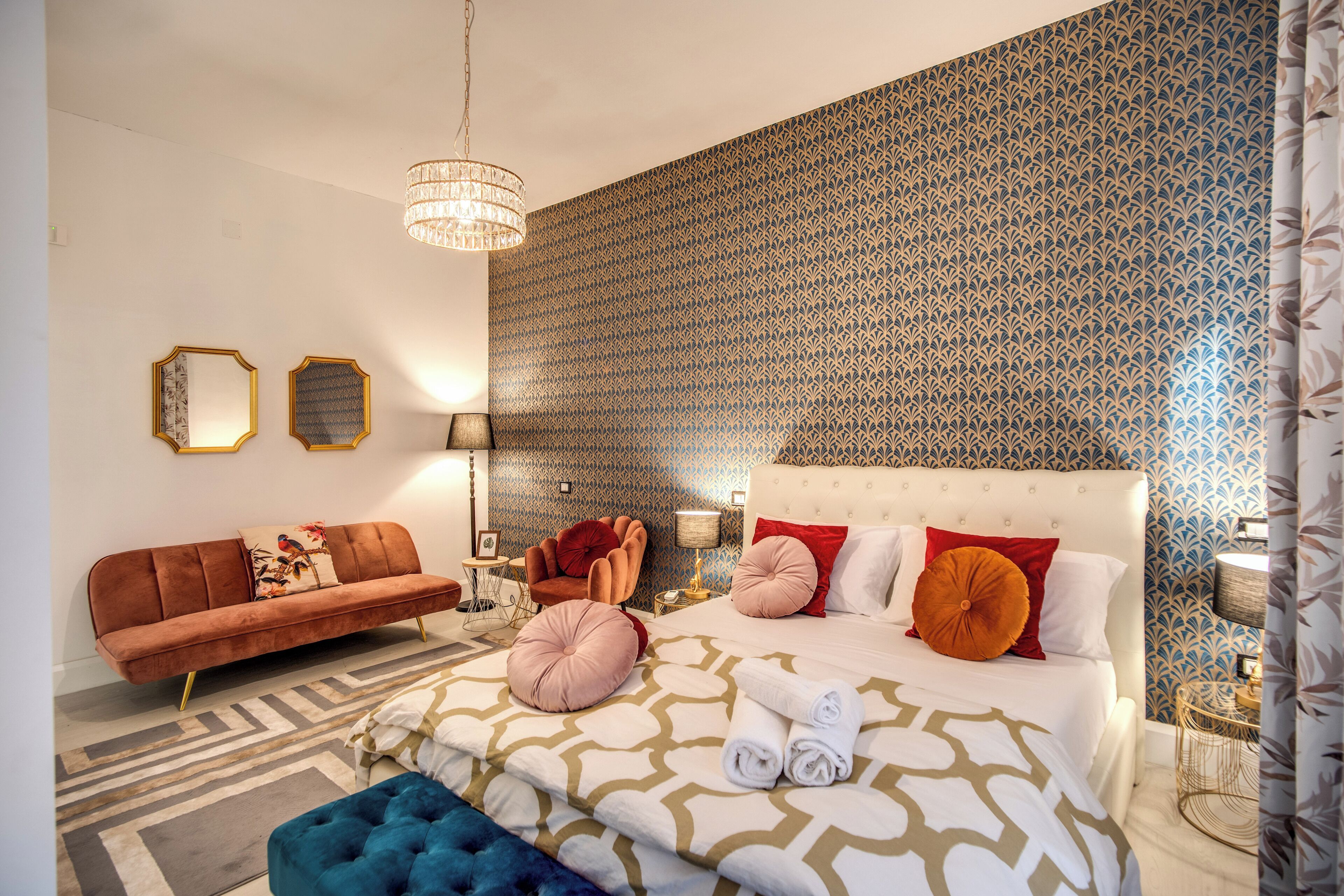 A modern bedroom with a large bed, a sofa, and a chair.