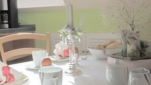 A dining table set with white plates, cups, and a vase with flowers. - Am Lustgarten Modern Retreat (Wernigerode)