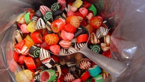 A variety of colorful candies in a clear container with a spoon. - 6 Person Holiday Home in Svaneke (Svaneke)