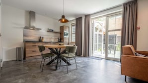 A modern kitchen with a wooden table and chairs, a hanging light fixture, and a sliding glass door leading to a balcony.