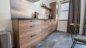 A modern kitchen with wooden cabinets, a stainless steel range hood, and a built-in oven.
