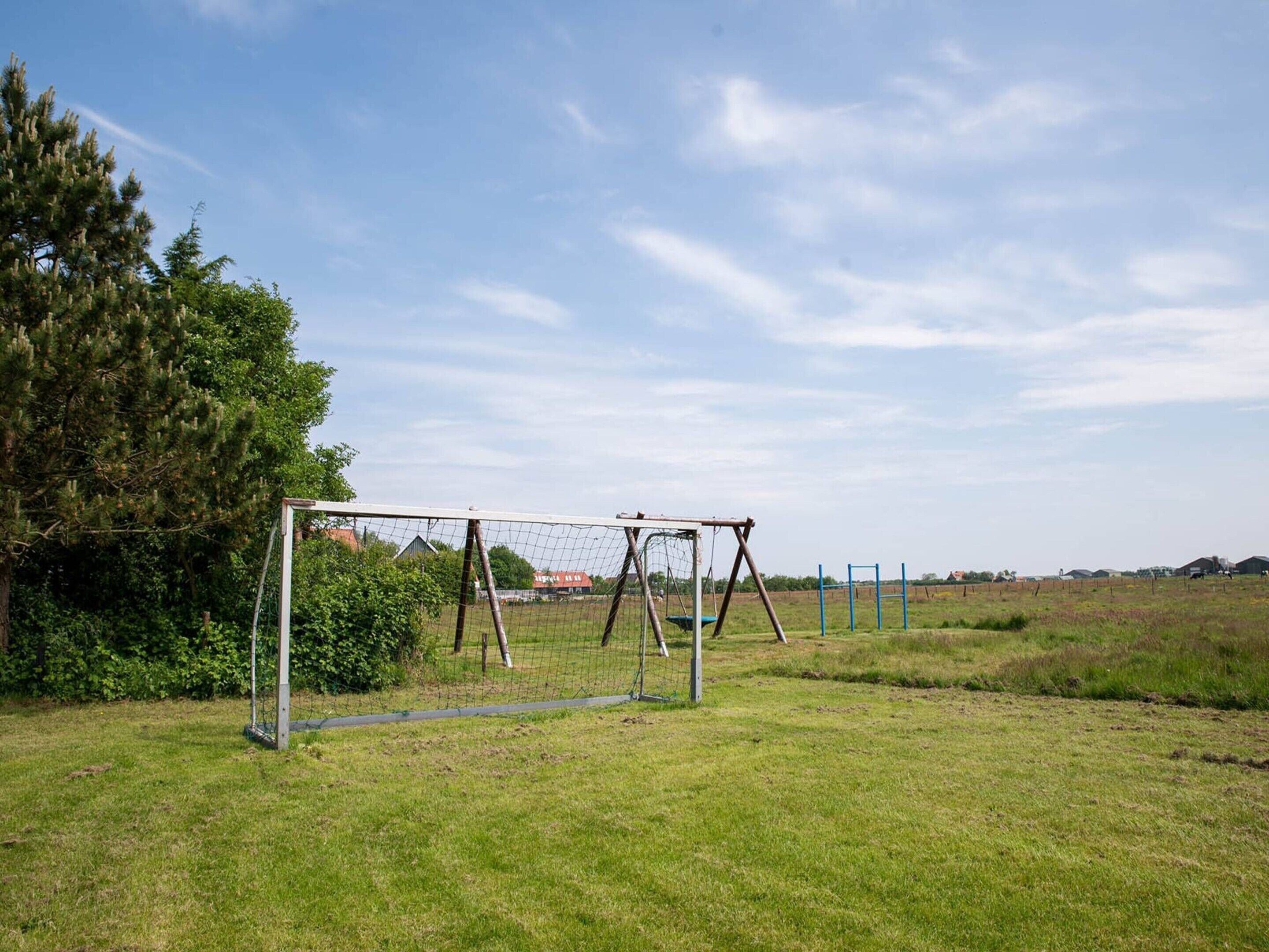 Un champ d’herbe avec des buts de football et des balançoires.