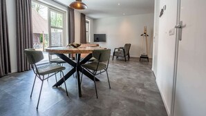 A modern dining area with a wooden table, four chairs, and a pendant light.