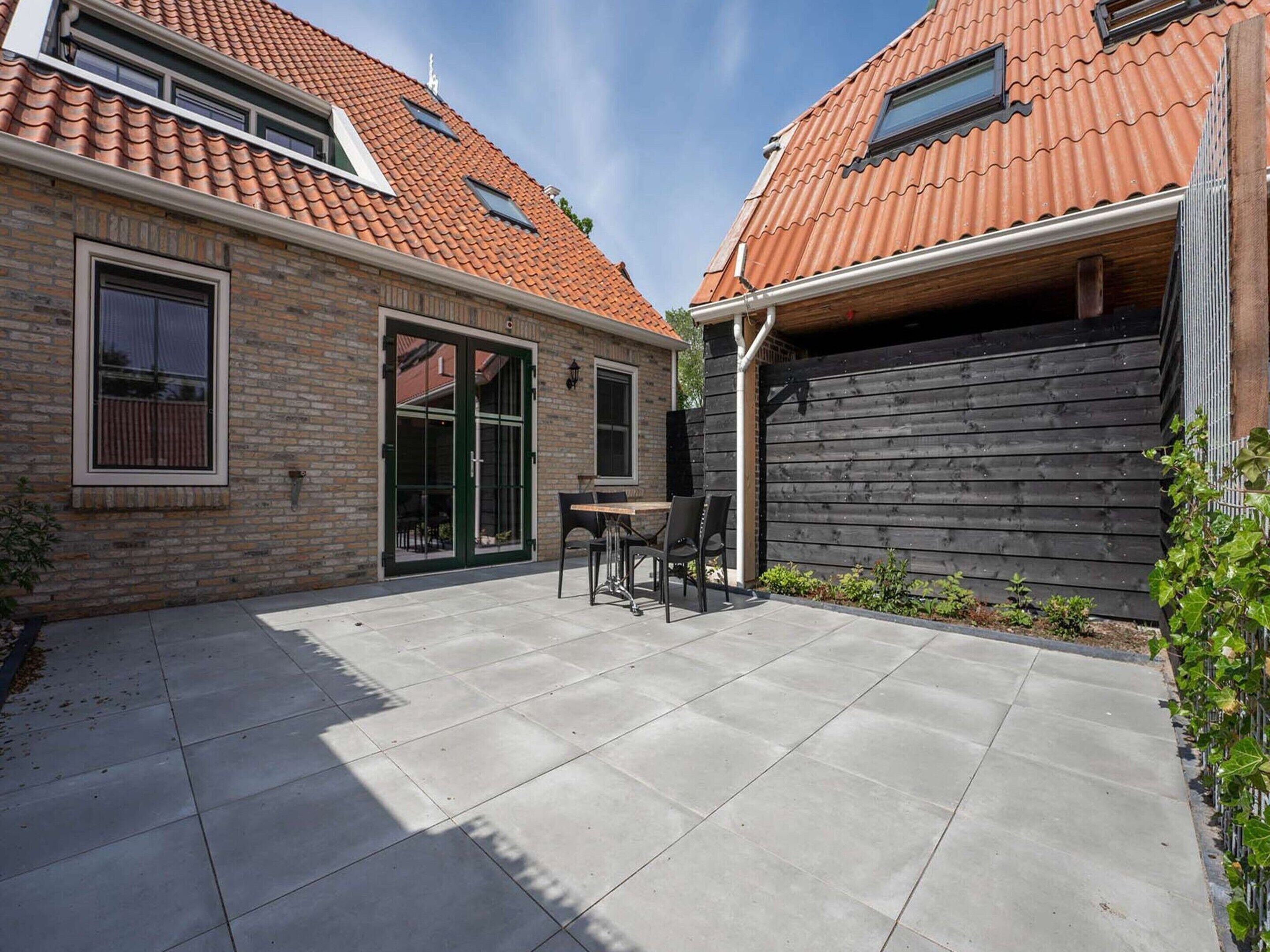 A patio area with a table and chairs, a sliding glass door, and a garage door.