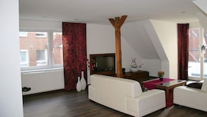 Un soggiorno moderno con un divano bianco, un tavolino in legno e una TV su un mobile in legno.