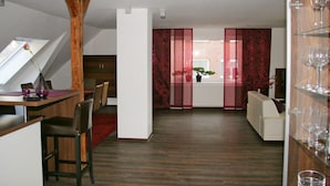 Zona pranzo moderna con tavolo in legno, sedie e una parete d'accento rossa.