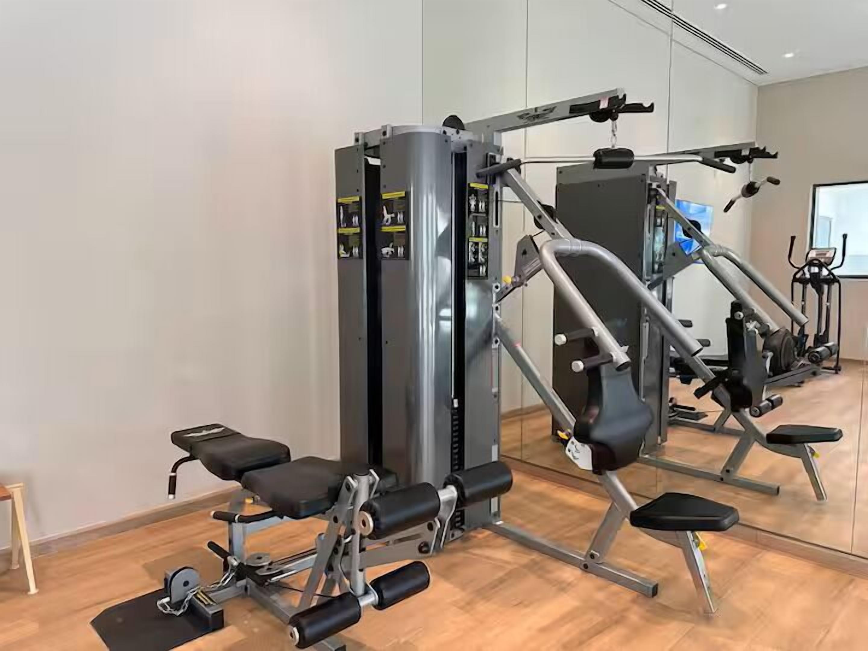 A gym with exercise machines, a bench, and a mirror.