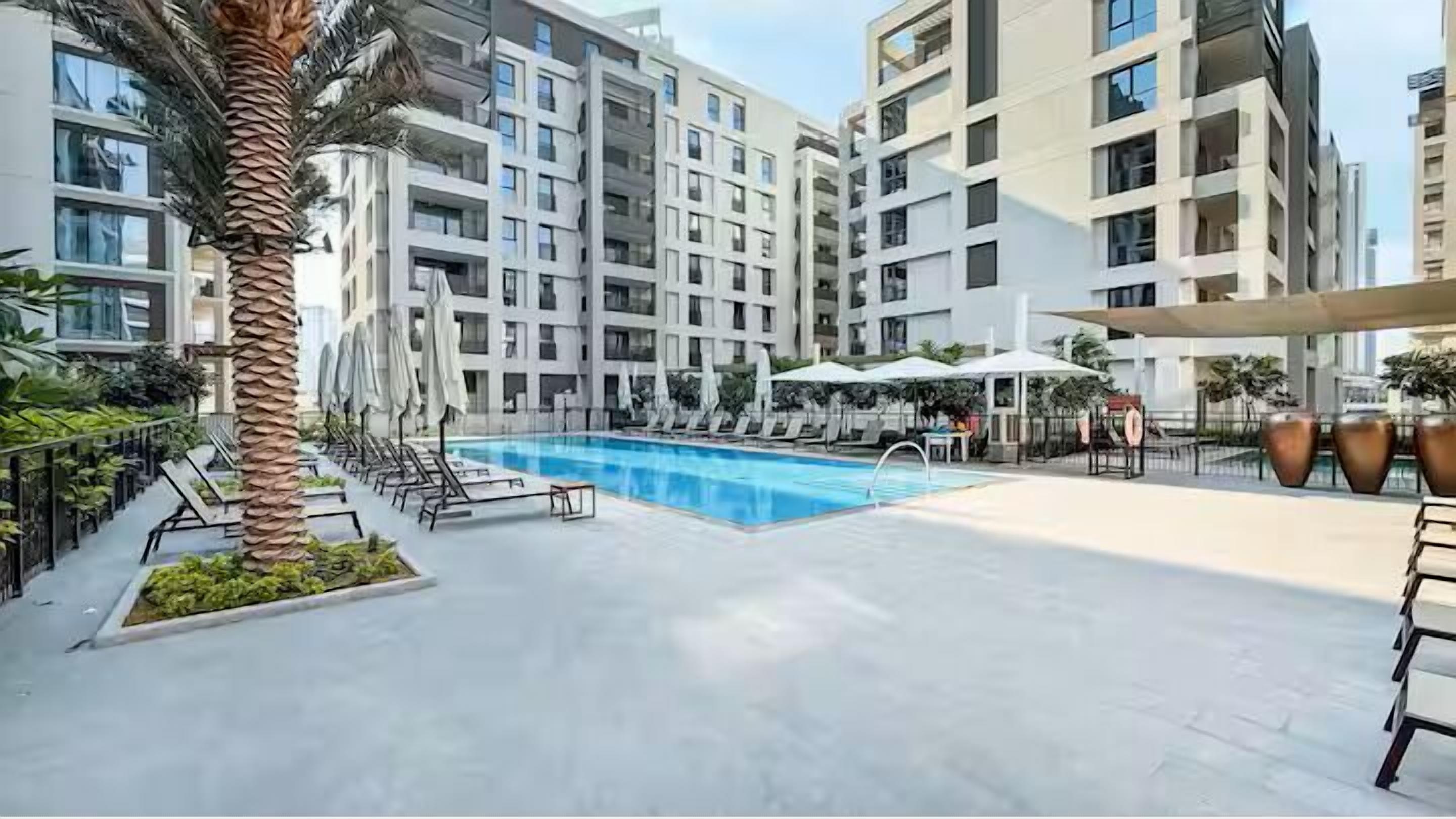 A modern hotel with a swimming pool, multiple balconies, and outdoor seating areas.