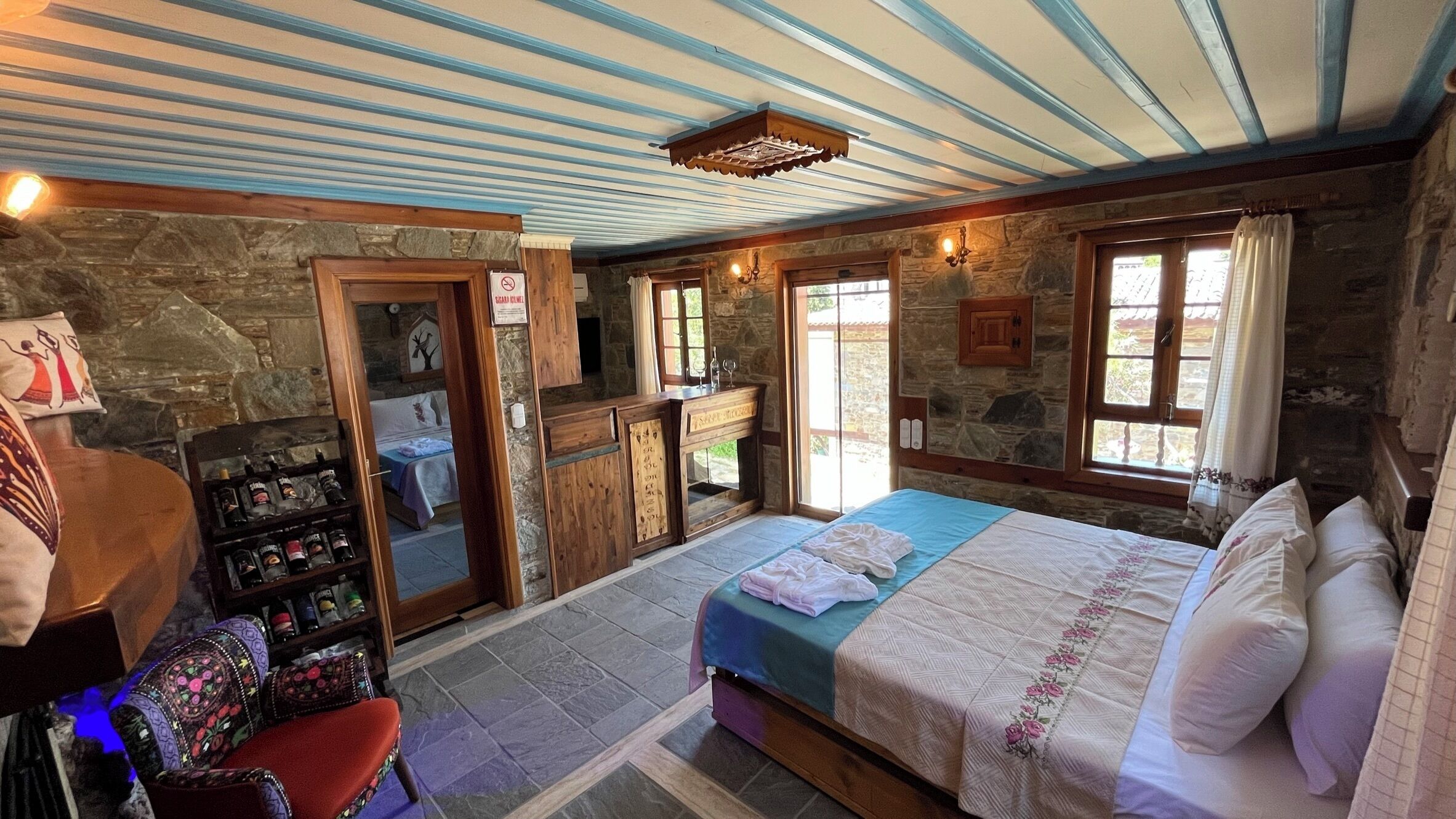 Habitació acollidora amb un llit, un taulell de fusta, una paret de pedra i una llar de pedra.