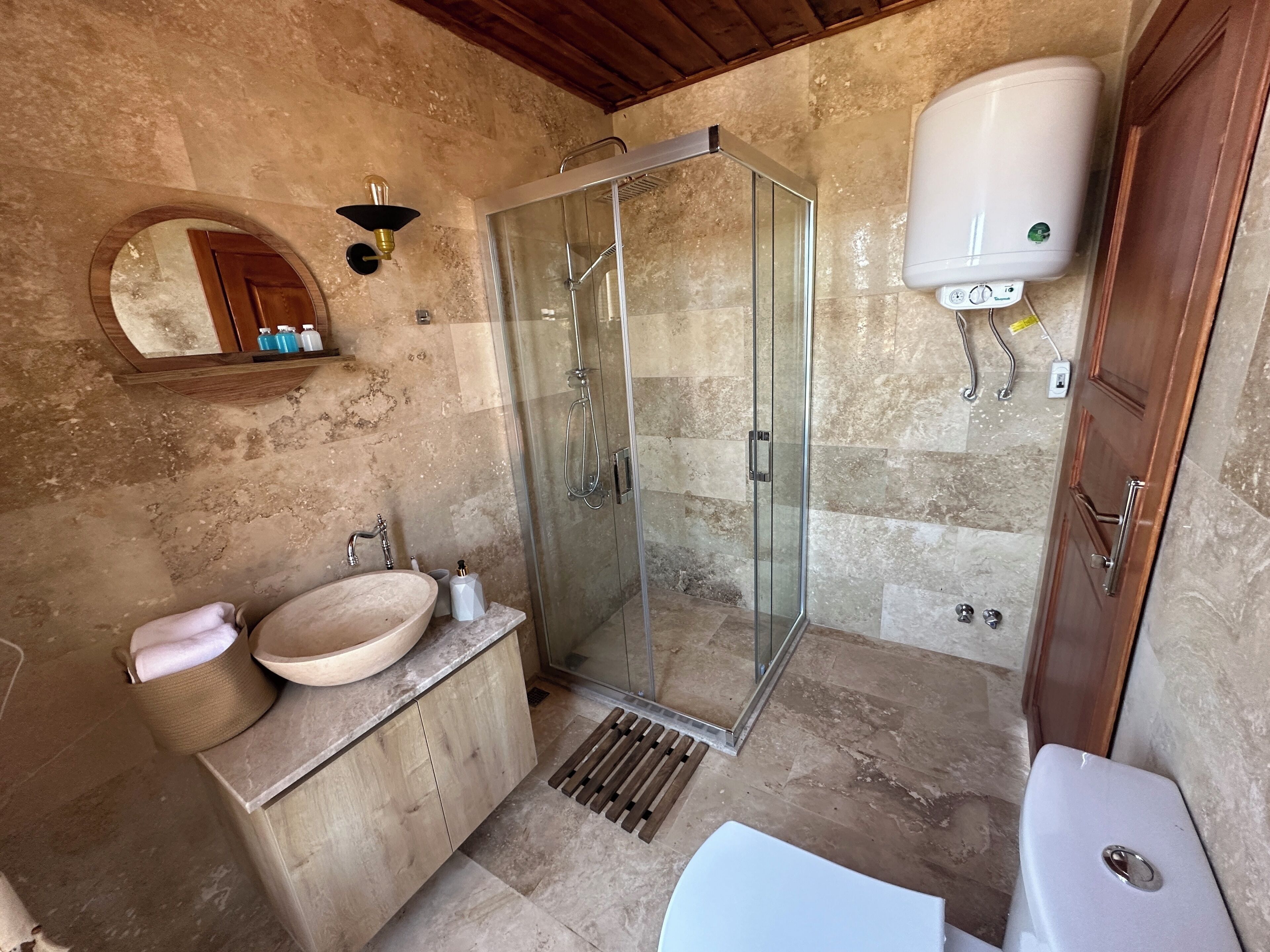 Ein Badezimmer mit Duschkabine, einem Holzwaschtisch mit Waschbecken und einer Toilette.