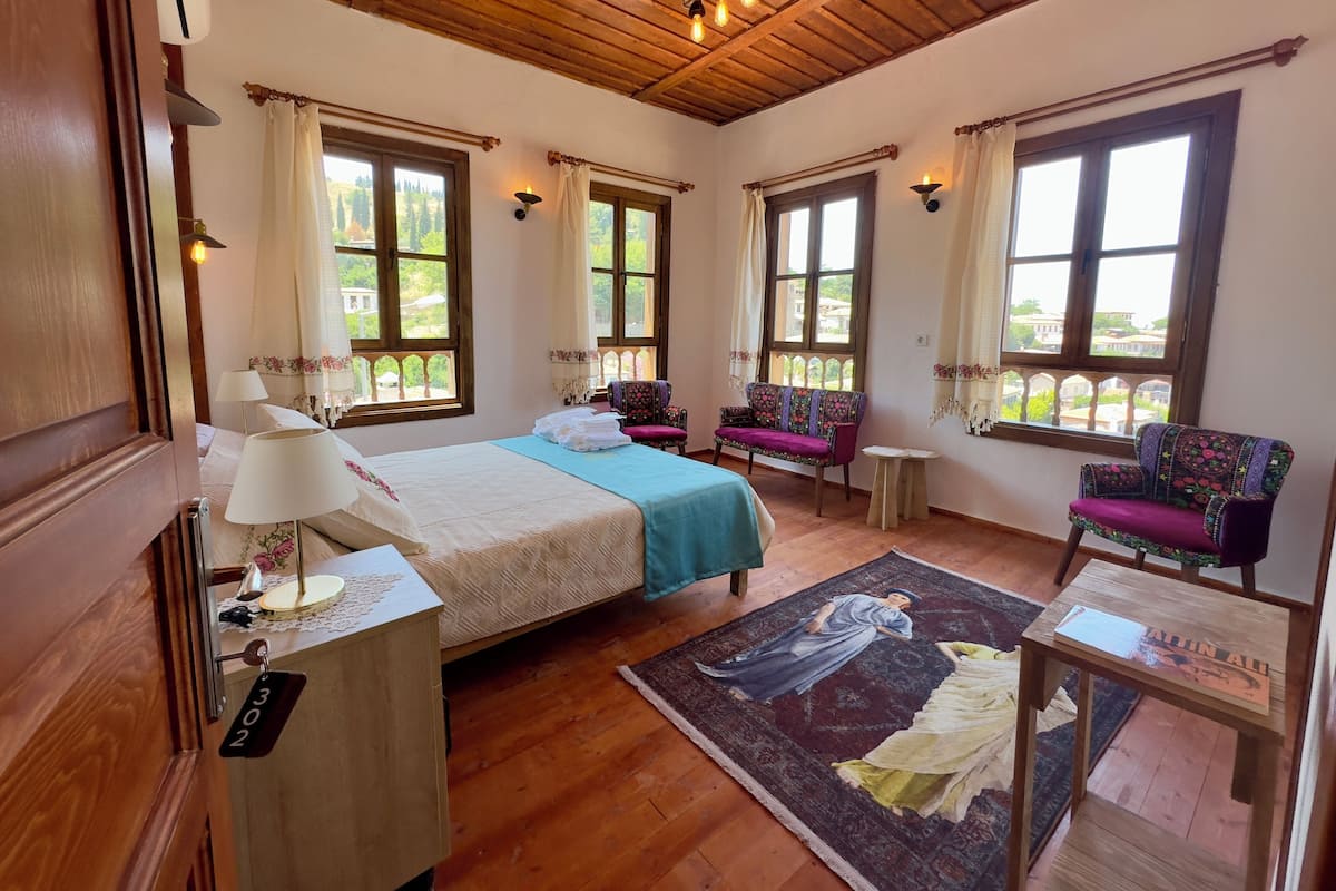 A room with a bed, two chairs, a small table, and a rug.