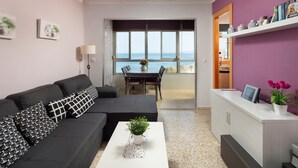 Una sala de estar moderna con sofá, mesa de centro y vista al mar a través de amplios ventanales.