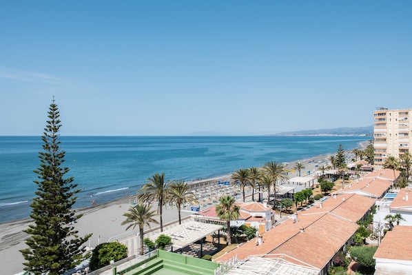 A coastal hotel with a beach view, multiple floors, and a mix of residential and commercial buildings.