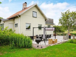 A house with a sloped roof, a patio with outdoor furniture, and a grill. - 4 Star Holiday Home in Brastad (Brastad)