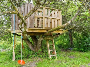 Una casa en árbol construida sobre un árbol grande con una plataforma de madera y escalera.