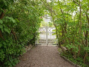 A pathway leading to a white gate surrounded by dense green foliage. - 4 Star Holiday Home in Brastad (Brastad)