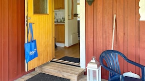 A wooden door with a blue bag hanging on the handle, a white lantern, and a blue chair outside a building with a red exterior. - 6 Person Holiday Home in Mardaklev-by Traum (Mårdaklev)