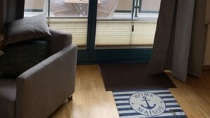 A room with a large sliding glass door leading to a balcony, a sofa, and a rug with a nautical theme. - Holiday Apartment Harbor Flair (Karlshagen)