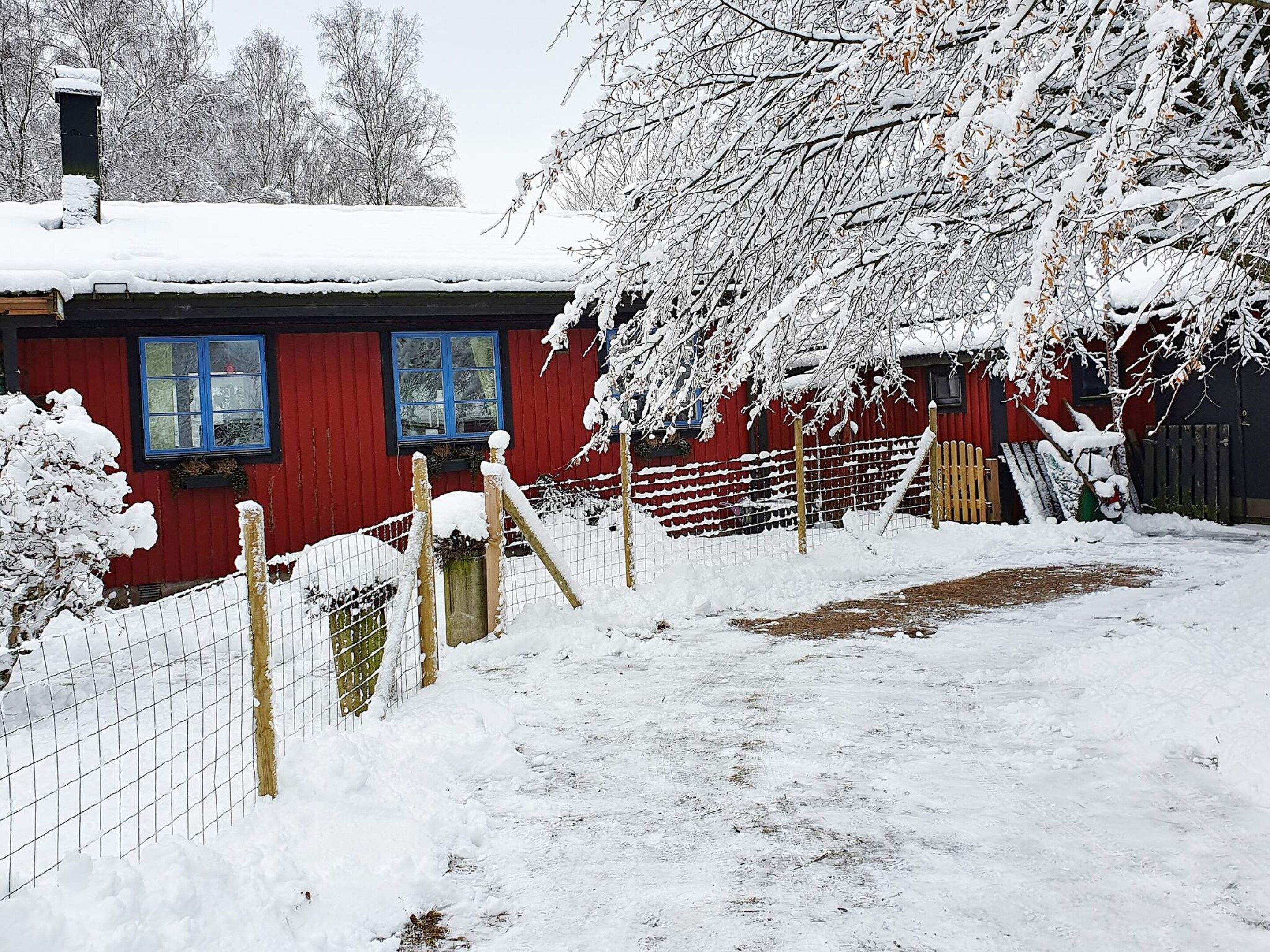 Un edificio rojo con techo nevado y patio cercado.