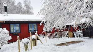 Una propiedad nevada con un edificio rojo, un patio cercado y una valla de madera.