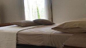 A single bed with a white bedspread and two pillows, a wooden headboard, and a window with curtains. - Cozy Apartment in Torrenova (Capri Leone)