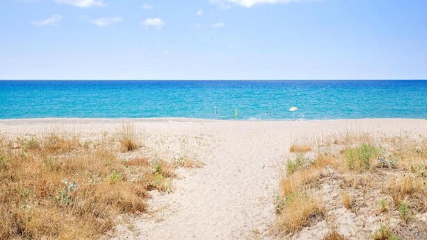 A beach with a clear path leading to the water, surrounded by dry grass. - Cozy Apartment in Torrenova (Capri Leone)