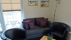 A living room with a grey sofa, two black leather chairs, a wooden coffee table with a potted plant, and two framed artworks on the wall. - Stefanie and Bernd Heumann (Cuxhaven)