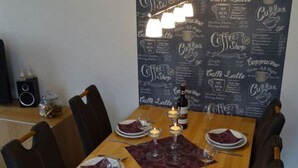 A dining area with a wooden table set for four, surrounded by black chairs. A menu wall with coffee and tea options is visible in the background. - Stefanie and Bernd Heumann (Cuxhaven)