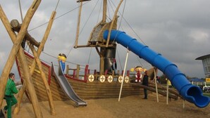 A wooden pirate ship play structure with a slide and a blue slide. - Stefanie and Bernd Heumann (Cuxhaven)