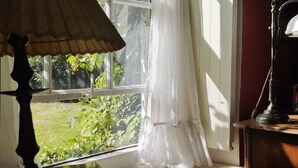 A room with a window, a lamp, and a view of greenery outside. - Orangery Berum Modern Retreat (Hage)