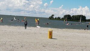 Una playa con gente practicando windsurf y vela.