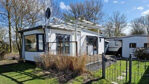 Una casa móvil moderna con fachada blanca, ventanas amplias y un porche cubierto.