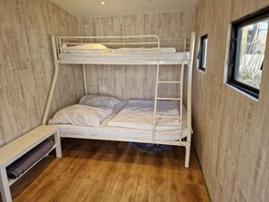 A bunk bed room with a wooden floor, a window, and a bench. - Blue Ocean K40 Comfortable Holiday Residence (Makkum)