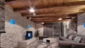 A modern living room with stone walls, a wooden ceiling, a flat-screen TV, a sectional sofa, and a marble floor. - Villa Patrick Comfortable Holiday Residence (Pazin)